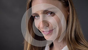 Face of young charming girl is watching at camera, winking, flirt concept, grey background