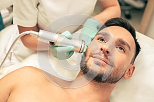 Young smiling man enjoying painless oxygen meso therapy photo