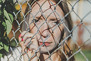 The face of a young girl behind a metal fence