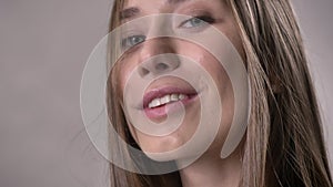 Face of young girl is watching at camera, smiling, flirt concept, grey background