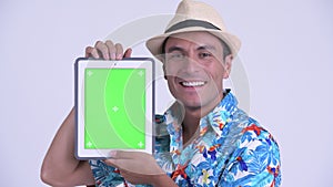 Face of young happy Hispanic tourist man showing digital tablet