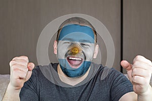 Face of young screaming  man painted with flag of Argentina.  Soccer team fan.