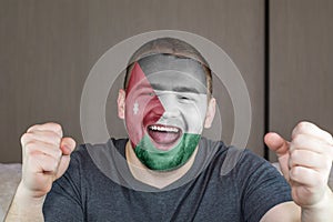 Face of young screaming man painted with flag of Jordan. Soccer team fan.