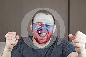 Face of young screaming man painted with flag of Slovakia. Soccer team fan.