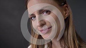 Face of young sweet girl is watching at camera, flirt concept, grey background