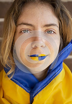 Face of a young woman with painted yellow-blue lips. Hope and faith, pride of the nation