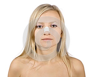 Face of young woman with sticking plaster on nose