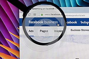 Facebook business homepage website on Apple iMac monitor screen under magnifying glass. Facebook is the most popular social
