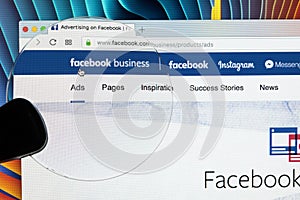 Facebook business homepage website on Apple iMac monitor screen under magnifying glass. Facebook is the most popular social
