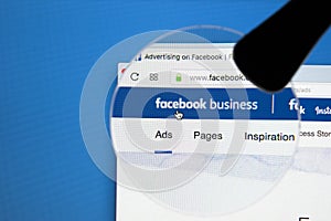 Facebook business homepage website on Apple iMac monitor screen under magnifying glass. Facebook is the most popular social