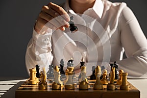 Faceless caucasian woman in white shirt playing chess.