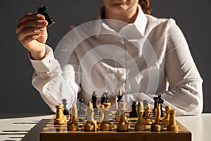 Faceless caucasian woman in white shirt playing chess.