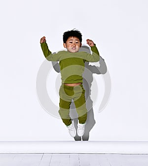 Faceless dark-haired little boy jumps on the background of a white wall in the studio.