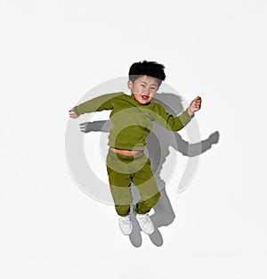 Faceless dark-haired little boy jumps on the background of a white wall in the studio.