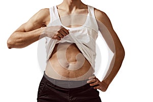 Faceless image of young male body, man showing belly muscles isolated over white background. Fitness. Concept of male