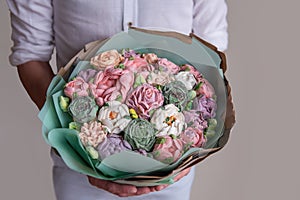 Faceless man holds bouquet of marshmallow sweet flowers in hands. sugarless roses, Hobby baking