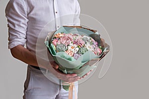 Faceless man holds bouquet of marshmallow sweet flowers in hands. sugarless roses, Hobby baking