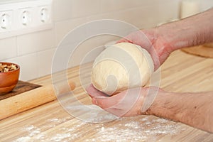 Faceless man kneading dough on kitchen table at home, apartment, flour, scales