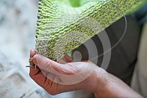 The faceless old woman knits. Close-up of female hands with straight and knitting needles.