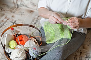 The faceless old woman knits. Close-up of female hands with straight and knitting needles.