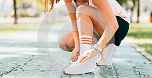 Faceless shot of a woman getting ready for running while tying shoes laces.