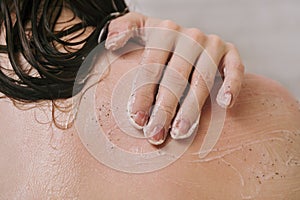 Faceless shot of woman using narutal scrub on her shoulder in the shower