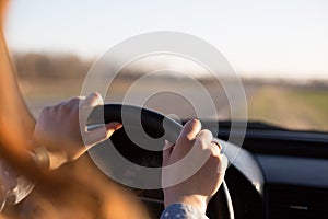 Faceless shot of young womans hands on steering wheel while driving the car, female stops her vehicle on side of road and enjoys