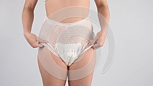 A faceless woman adjusts the elastic of adult diapers. Incontinence problem.