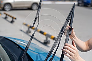 Faceless woman changing car windshield wipers.