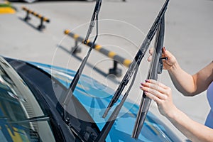 Faceless woman changing car windshield wipers.