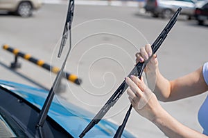 Faceless woman changing car windshield wipers.