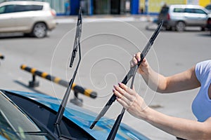 Faceless woman changing car windshield wipers.