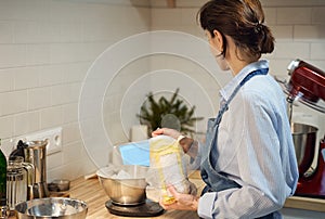 Faceless woman cooking and baking dough on kitchen table at home,