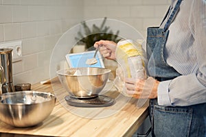 Faceless woman cooking and baking dough on kitchen table at home,