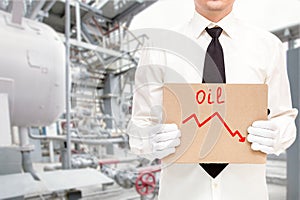 Faceless worker in work gloves holds a poster with a graph of the fall in oil prices.