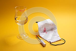 Facemask kiss mark, wineglass with lips impression on yellow