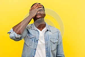 Facepalm, I forgot. Portrait of regretful man holding hand on face. indoor studio shot  on yellow background