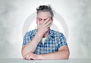 Facepalm man, Portrait male in plaid shirt sitting at a table, epic fail emotion.