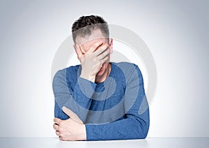 Facepalm man, Portrait male in T-shirt sitting at a table, epic fail emotion