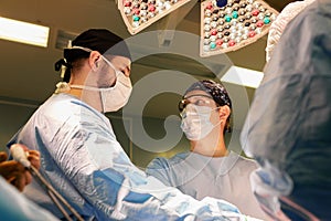 The faces of doctors surgeons in masks are a big plan, an operating room, a surgeon performs an operation in a modern