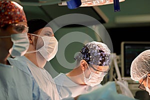The faces of doctors surgeons in masks are a big plan, an operating room, a surgeon performs an operation in a modern