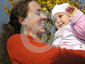 Faces mother with baby on autumn leaves