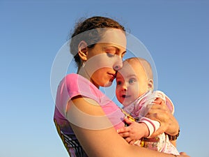 Faces mother with baby on sunset touch nose