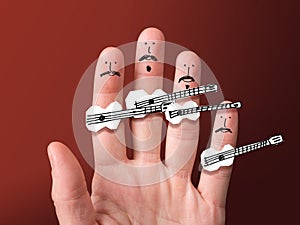 Faces painted on fingers. Mustachioed musicians hold paper guitars