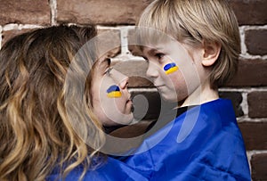 Faces in profile of a boy and a young woman with a blue and yellow flag painted on their cheeks