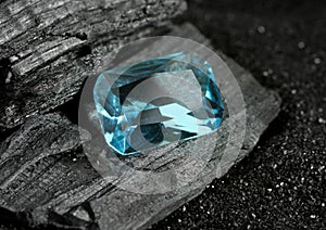 Faceted blue jewelry gemstone aquamarine on black coal background photo