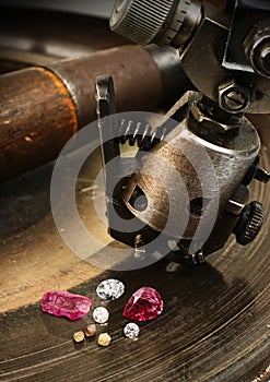 Faceting gemston, big diamond with jewelery equipment on background. Jewellery manufacture.