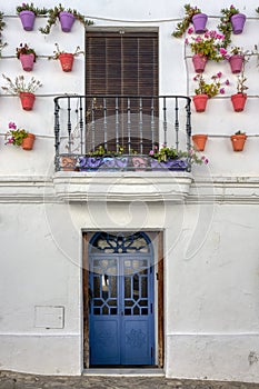 Traditional Andalusian village facade decorated with pots, with blue wooden door and balcony, in Vejer de la Frontera, Spain photo