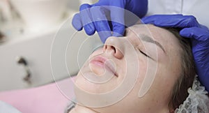 Facial anti wrinkle skin care. Close up of young woman at cosmetology clinic, having beauty procedures. Hands of