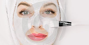 Facial beauty treatment. Closeup of pretty woman getting mask at spa salon. Cropped image of special brush in hands of